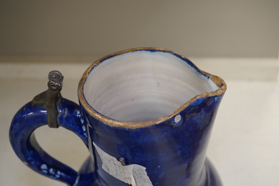 An 18th century German blue glazed faience jug with pewter lid, 30cm. Conditon - poor to fair